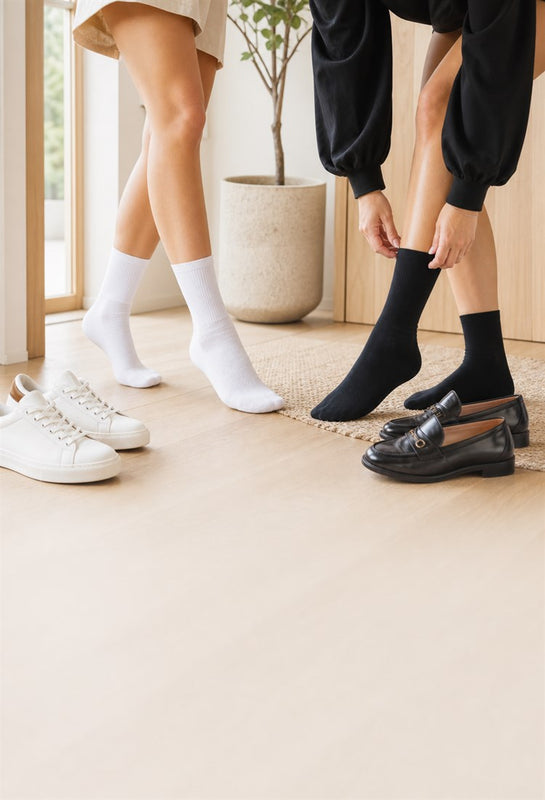 Two women wearing white and black comfort socks in a bright modern entryway